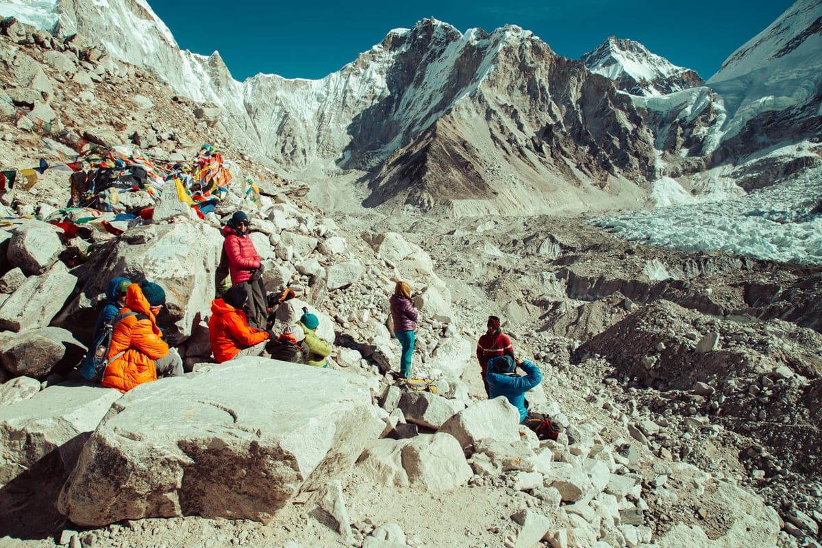 Trekkers resting at Everest Base Camp among prayer flags and snowy peaks