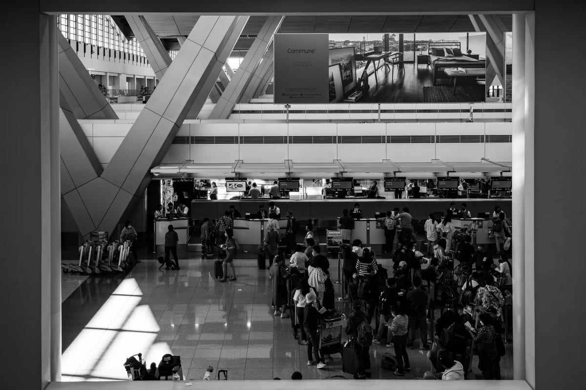 Black and white photo of travellers walking through a busy airport terminal