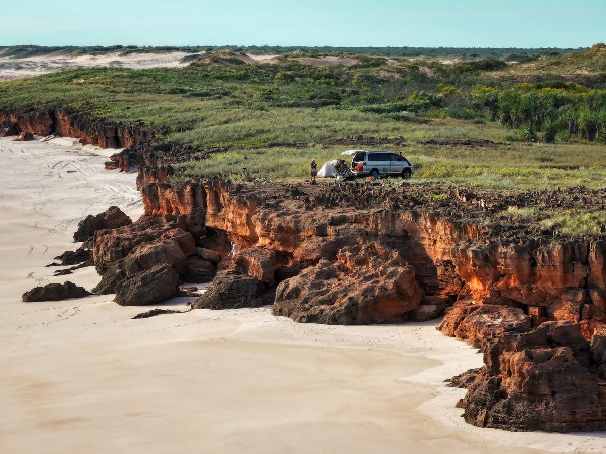 Campervan and tent on red cliffs above a white beach on the Dampier Peninsula, Western Australia