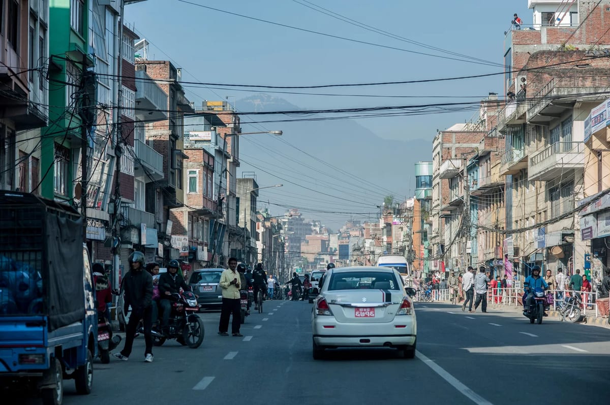 A busy street in Kathmandu with traffic, shops and power lines