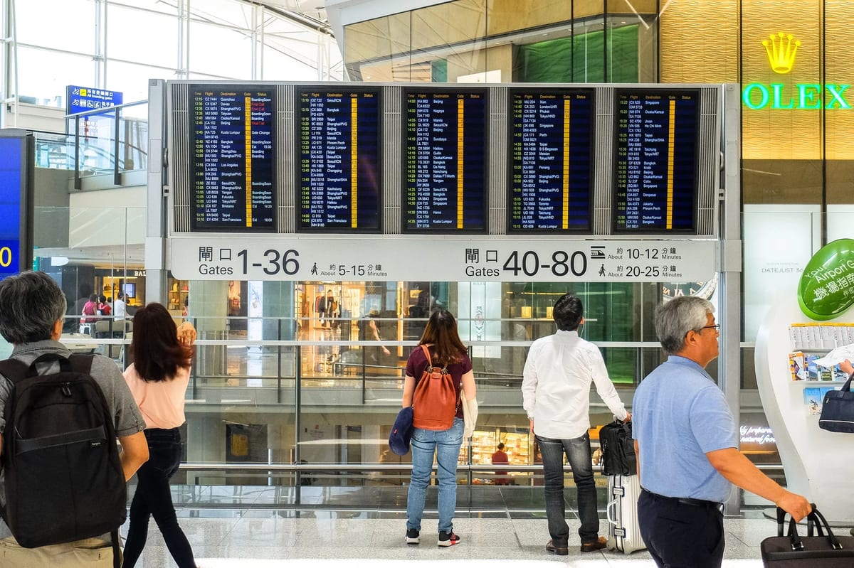 Passengers checking the departure board at Hong Kong International Airport