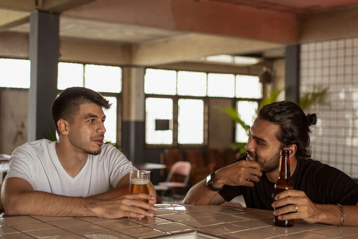 Two friends talking over a beer in a bright cafe