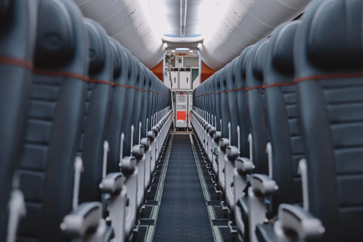 The empty aisle of an airliner cabin between rows of seats