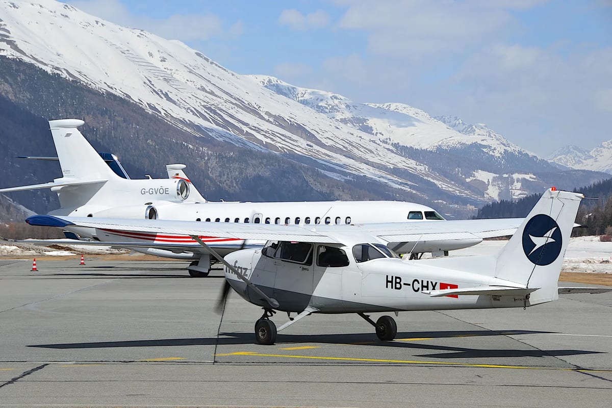 Small aircraft parked on a cleared apron below snow-covered mountains