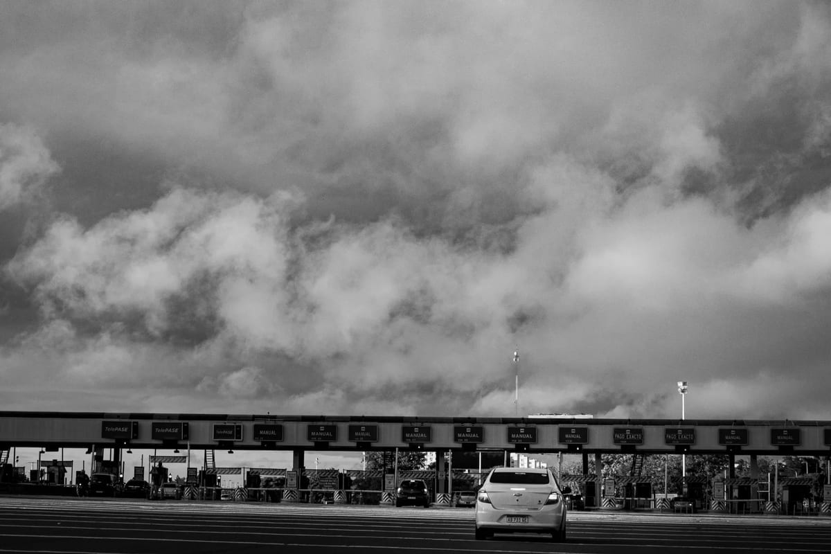 A black and white photo of a car approaching a motorway toll booth