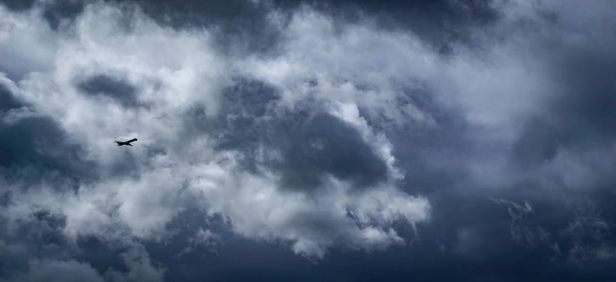 Airplane flying through dramatic storm clouds