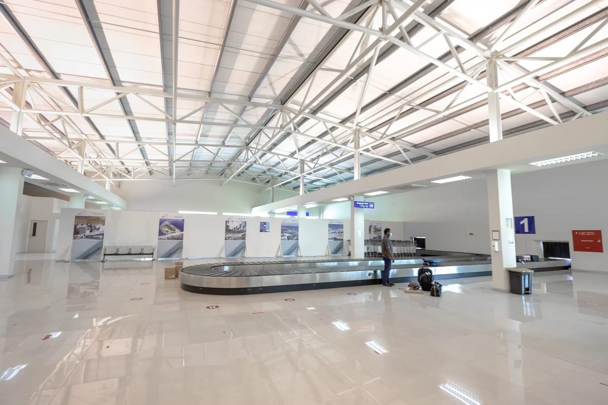 Empty airport baggage claim area with a traveller waiting
