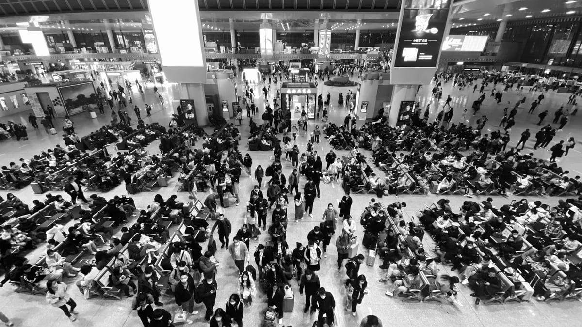 High-angle black and white view of a crowded airport terminal with passengers waiting