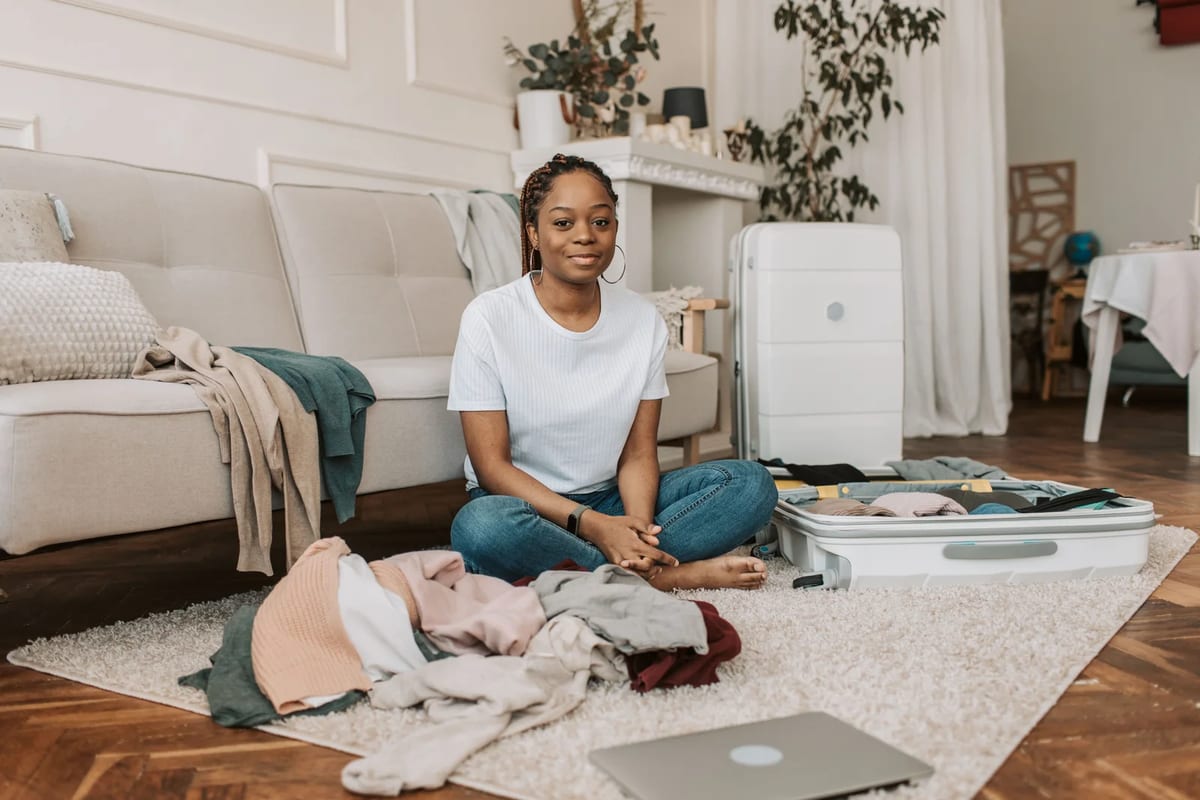 Woman sitting on a living-room rug packing a suitcase for a trip