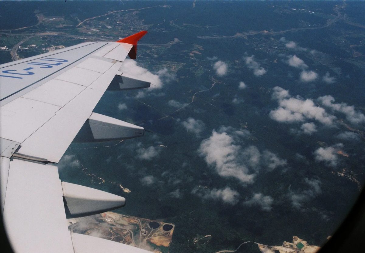 View over an aircraft wing of clouds and landscape far below