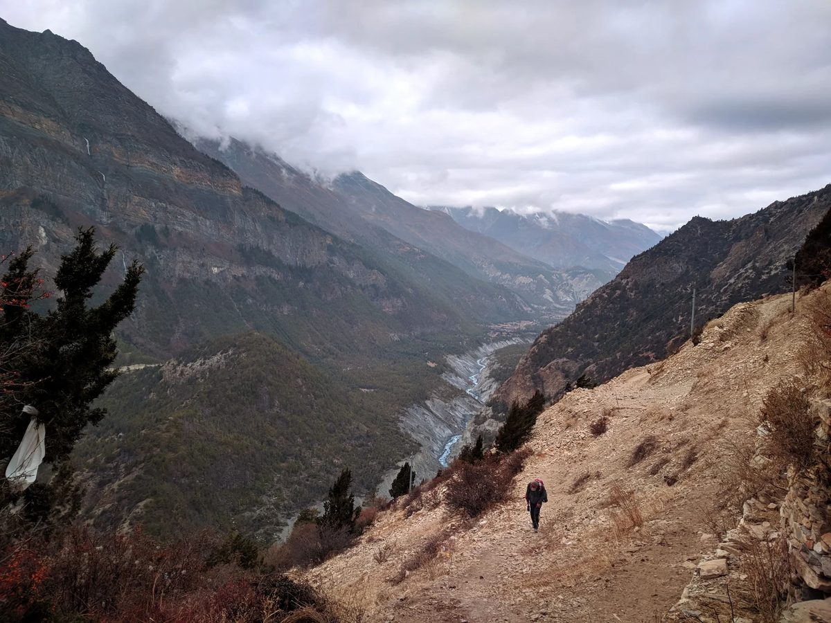 Traveller walking a rugged trail in Nepal under cloud