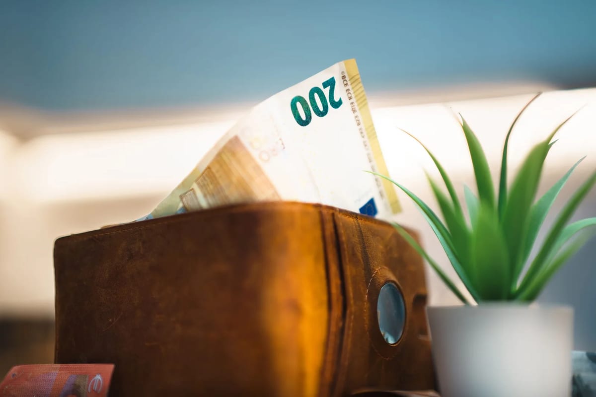 Euro banknotes tucked into a brown leather wallet