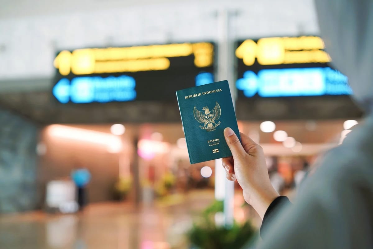 A traveller holding an Indonesian passport at an airport terminal