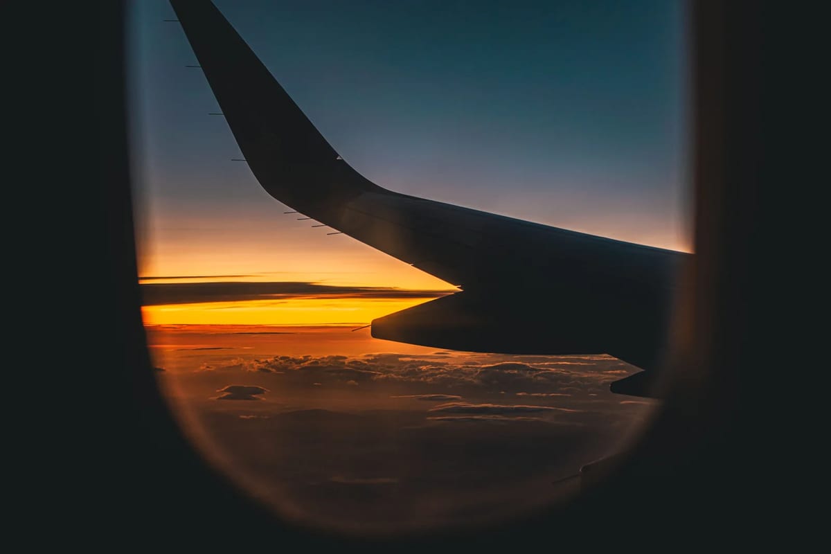 An airplane wing against a sunset sky