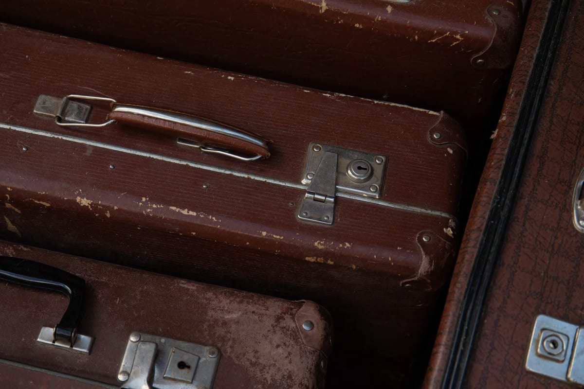 Close-up of worn brown suitcases with scuffed corners and metal clasps