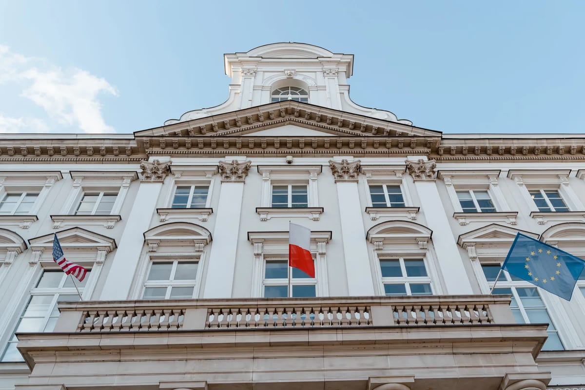 A classical building facade hung with several national flags