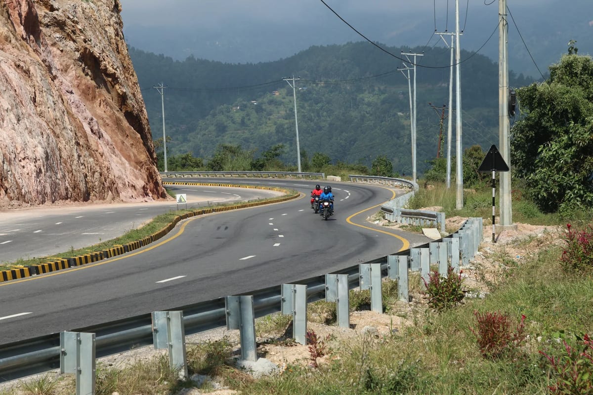 A winding road cutting through the hills of Nepal under a clear sky
