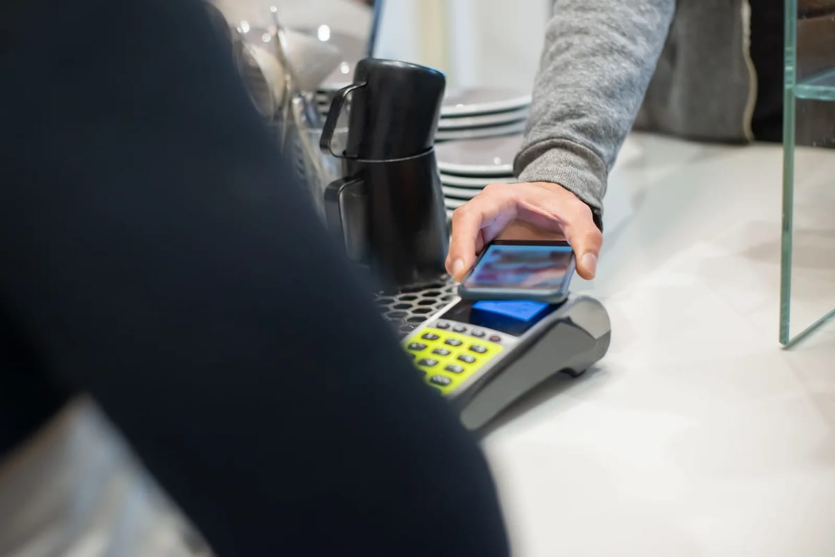 Customer paying with a smartphone at a cafe counter