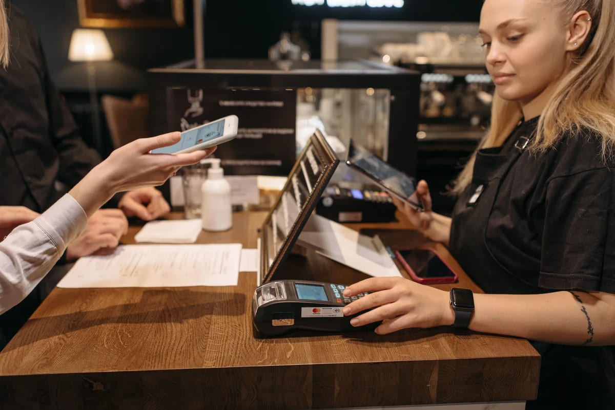 Customer using a mobile phone for contactless payment at a coffee shop