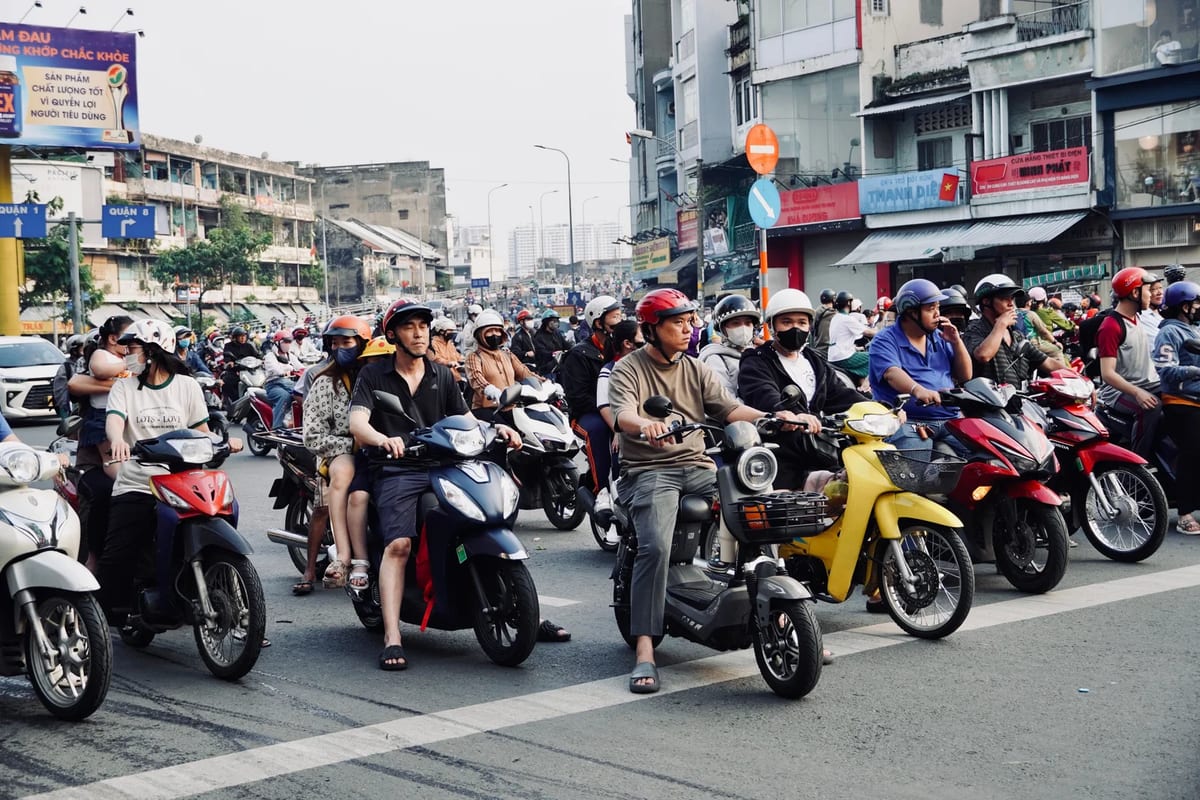 Scooter riders in helmets waiting at a busy city junction