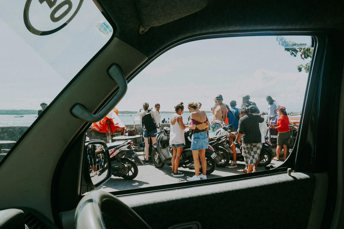Travellers standing beside parked scooters by the sea