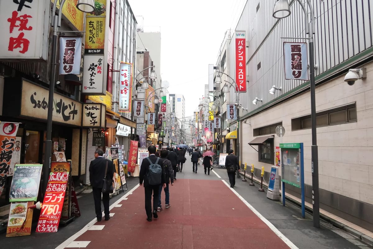 Shoppers walking down a Tokyo street lined with shop signs