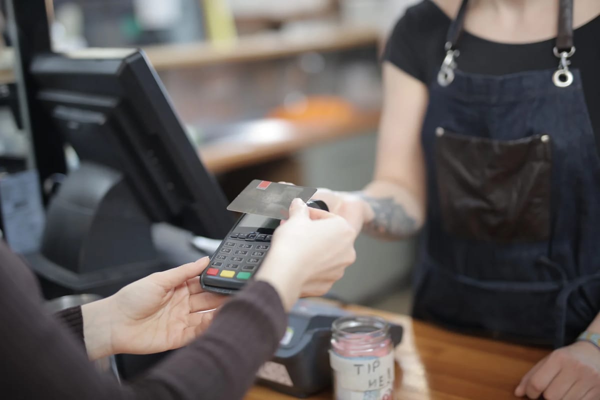 A customer handing a credit card to a cashier at a shop counter