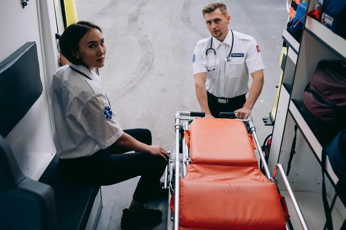 Two paramedics preparing a stretcher inside an ambulance