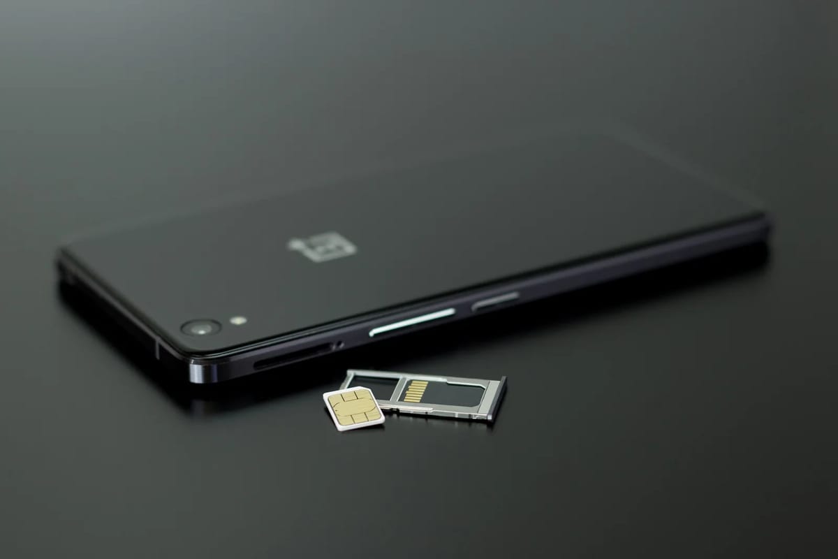 A smartphone with a SIM card and memory card beside it