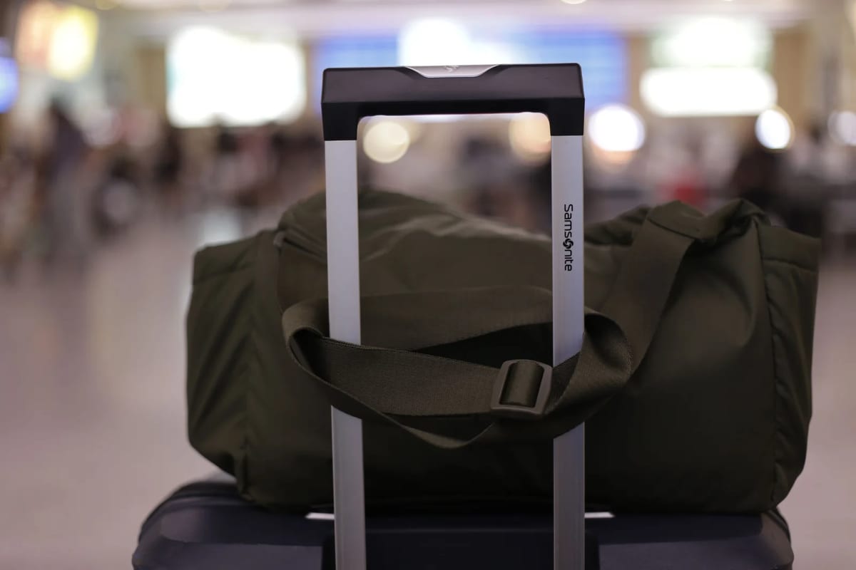 A suitcase and duffel bag in a busy airport