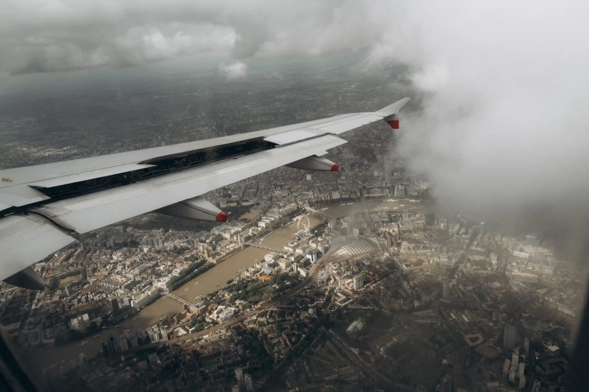 Aircraft wing over London seen from a plane window, with the Thames below