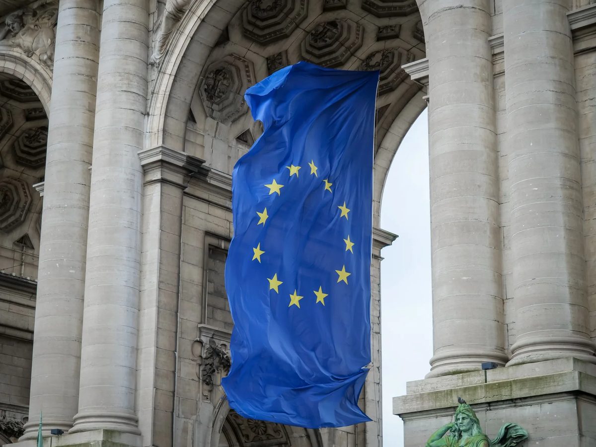 European Union flag hanging beneath a stone arch in Brussels