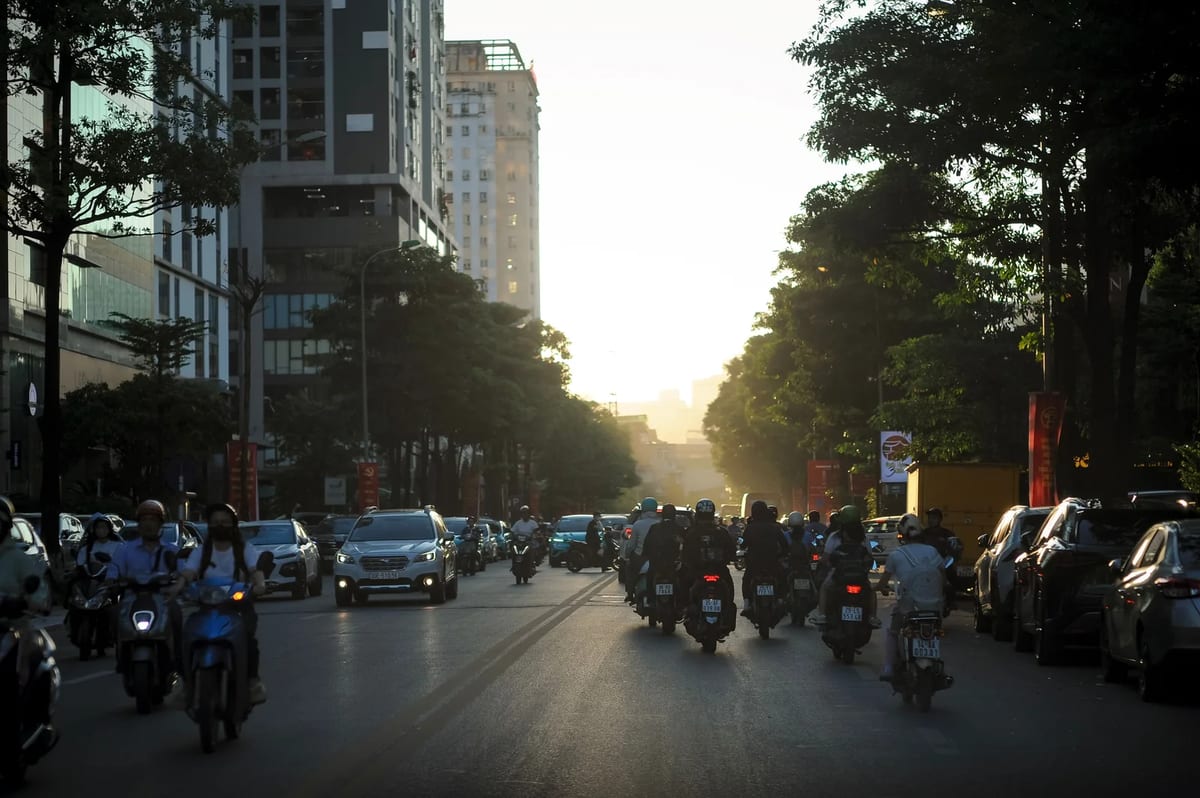 A busy street in Hanoi at sunset, with cars and motorbikes