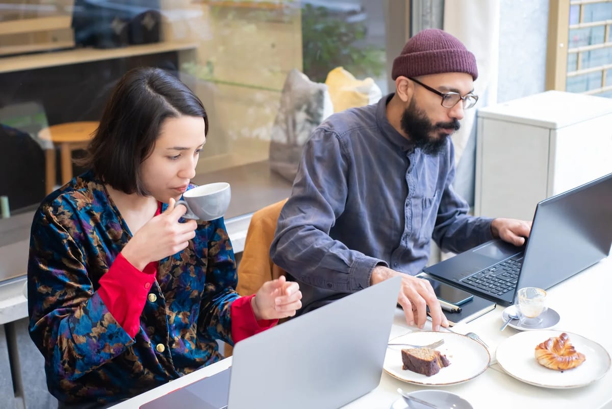 Two people working on laptops in a cafe