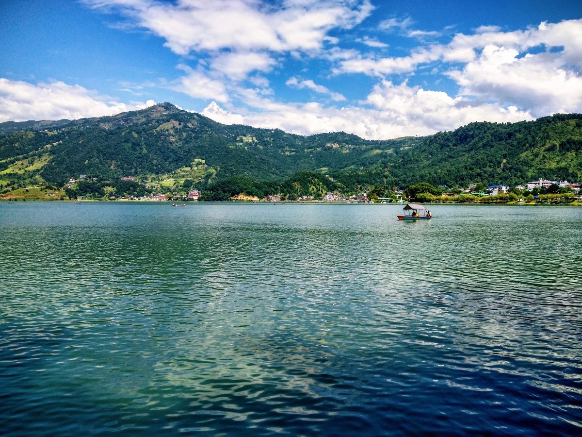 Phewa Lake in Pokhara with green hills under a blue sky