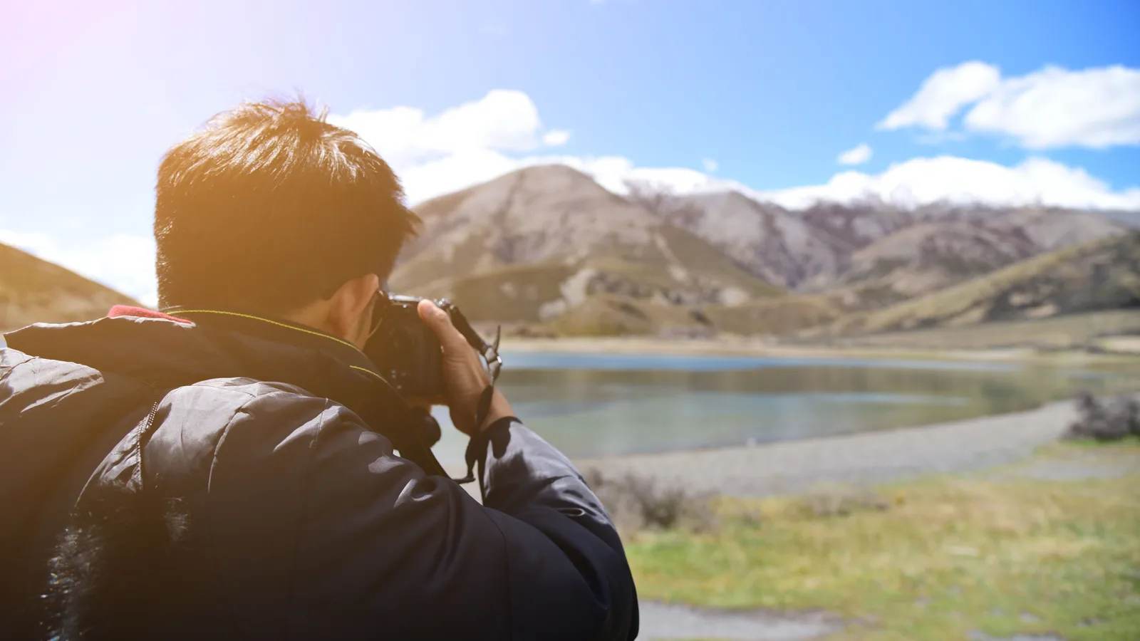 A photographer shooting a mountain lake on a sunny day