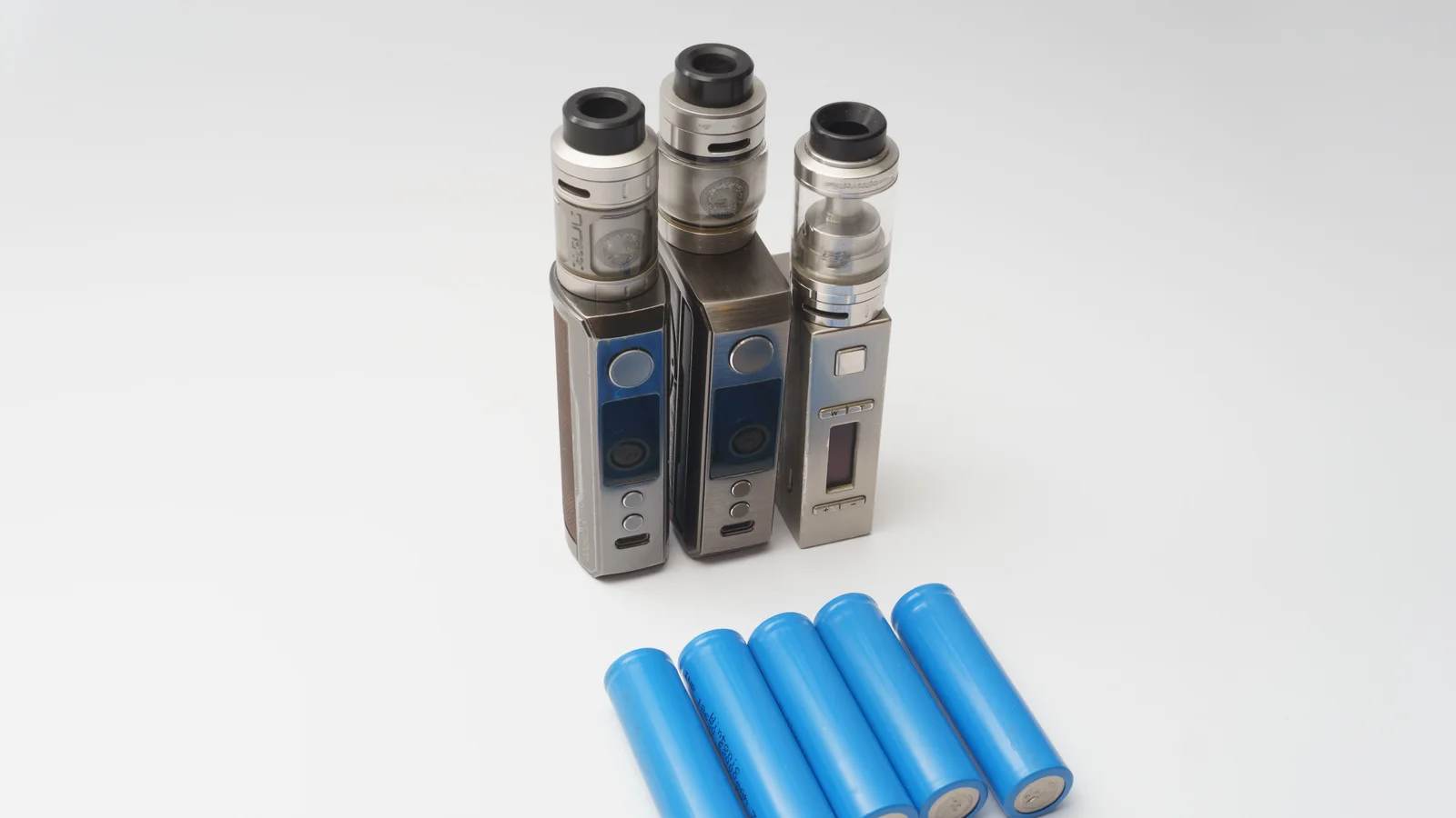 Three vape mods and blue lithium-ion batteries on a white surface