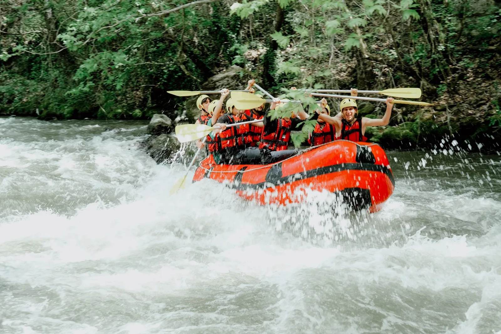 A rafting crew paddling hard through white-water rapids — the kind of adventure activity that standard travel insurance excludes unless you add specialist cover