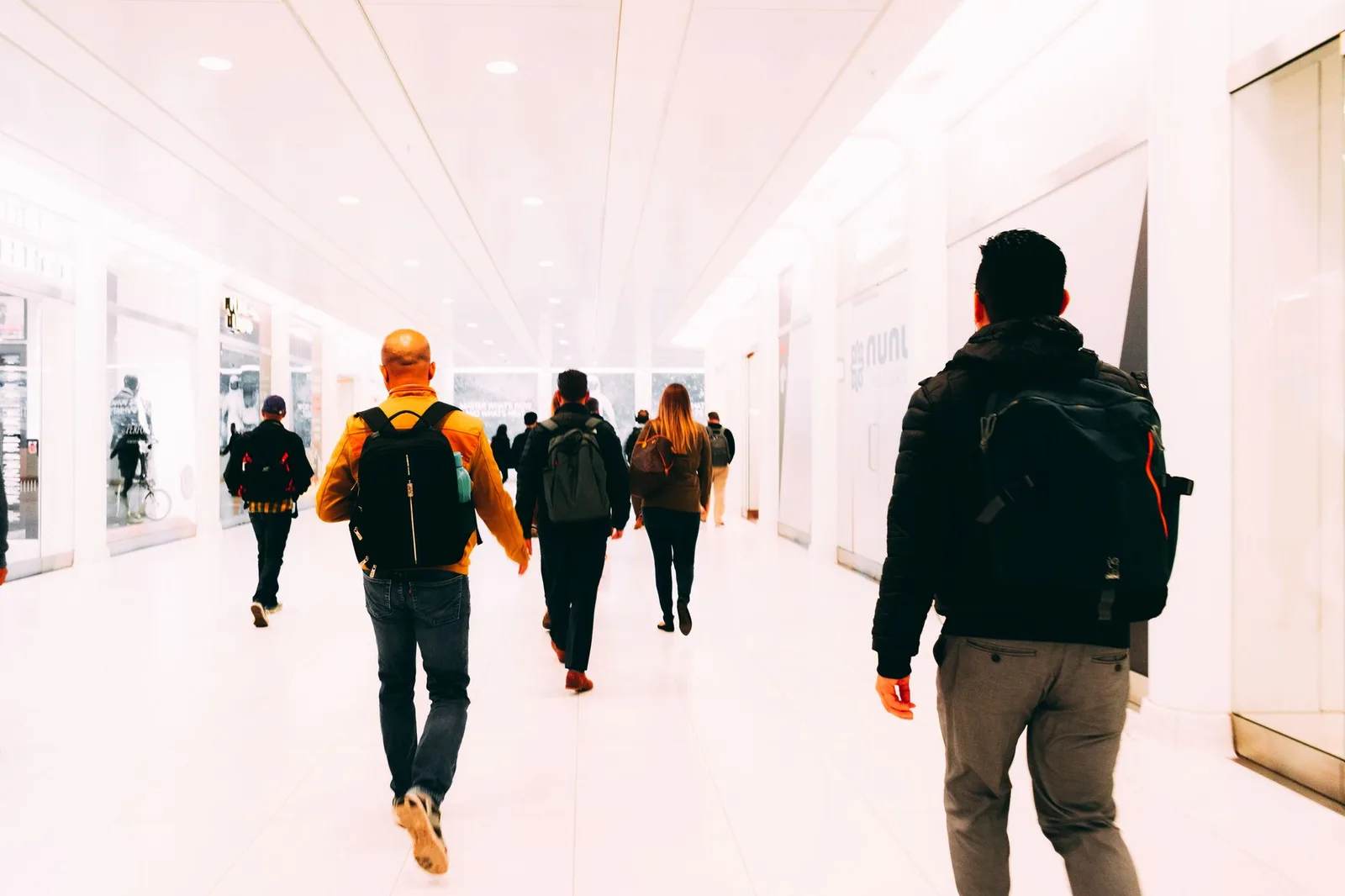 Travellers carrying backpacks walk through a bright modern airport terminal
