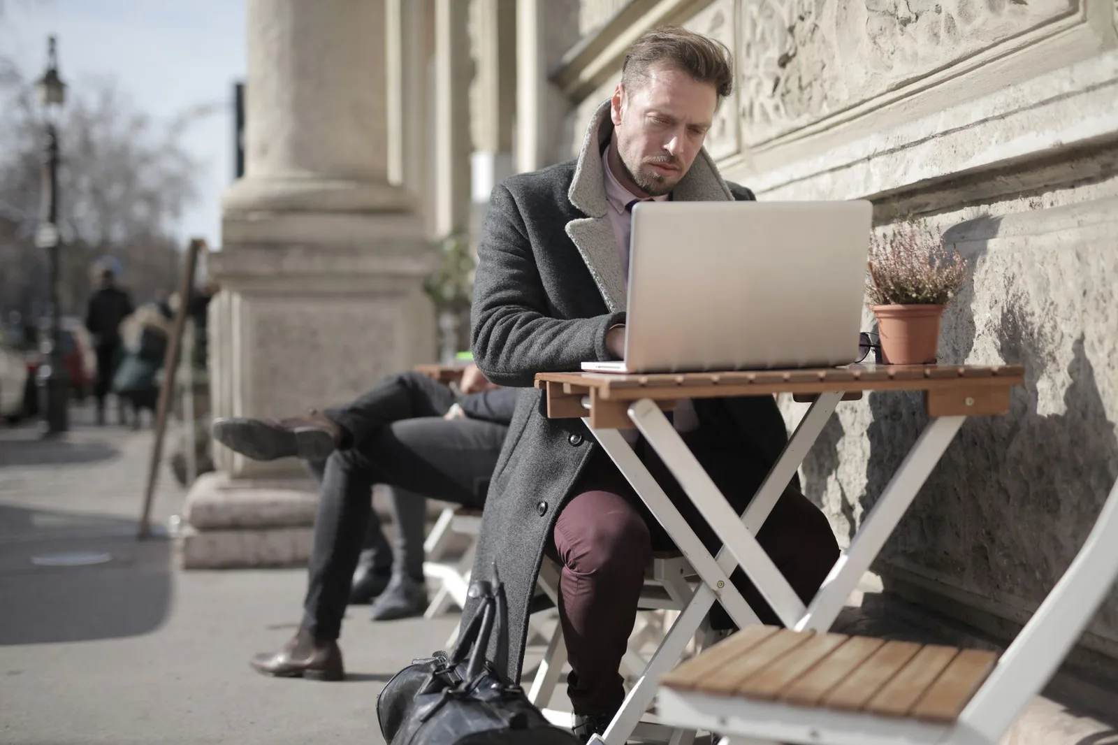 A remote worker with a laptop at an outdoor table in a city — the digital-nomad lifestyle, 2026