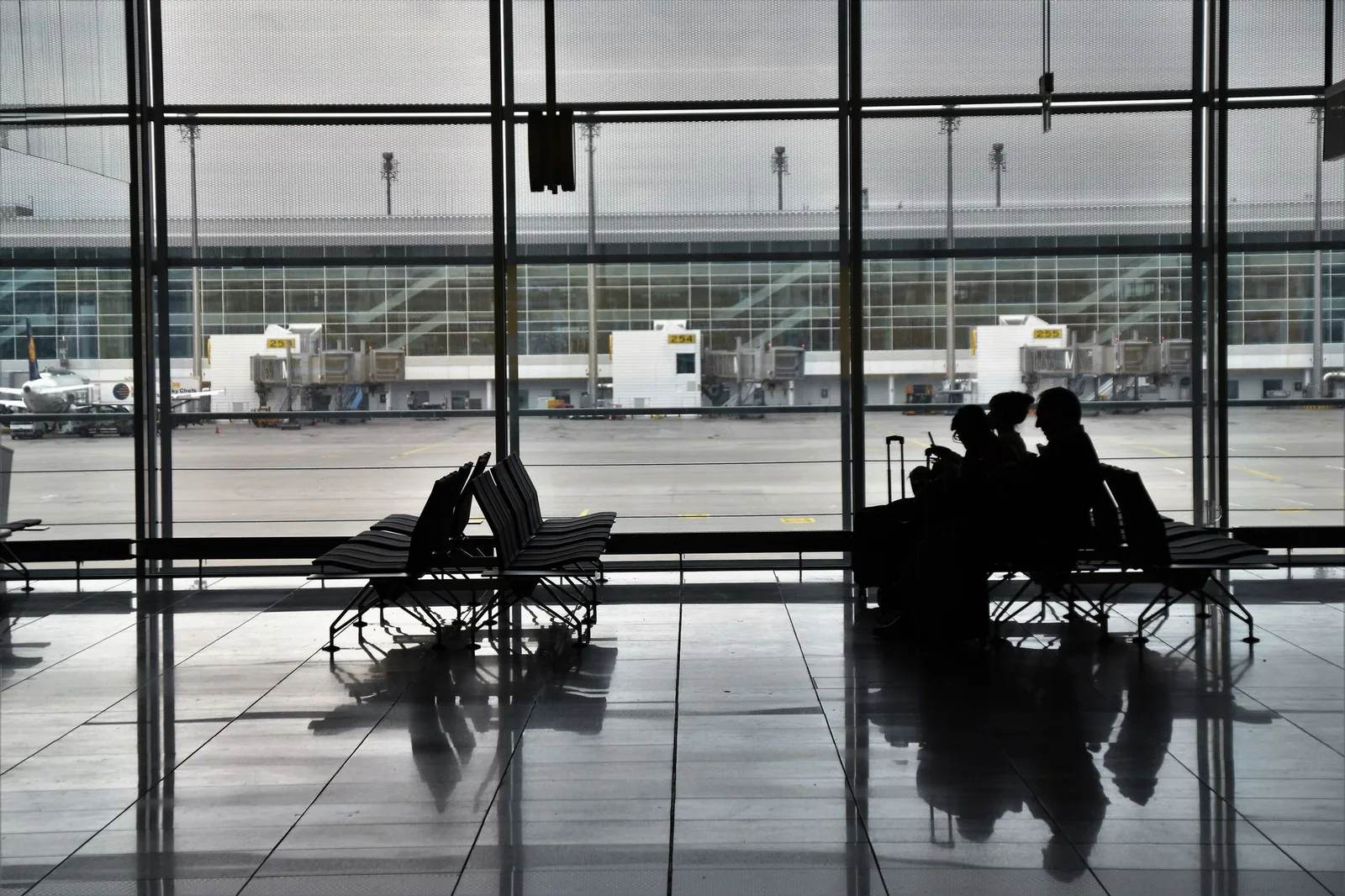 A family with young children and luggage walking through an airport terminal — illustrative of one family travel insurance policy covering parents and their children