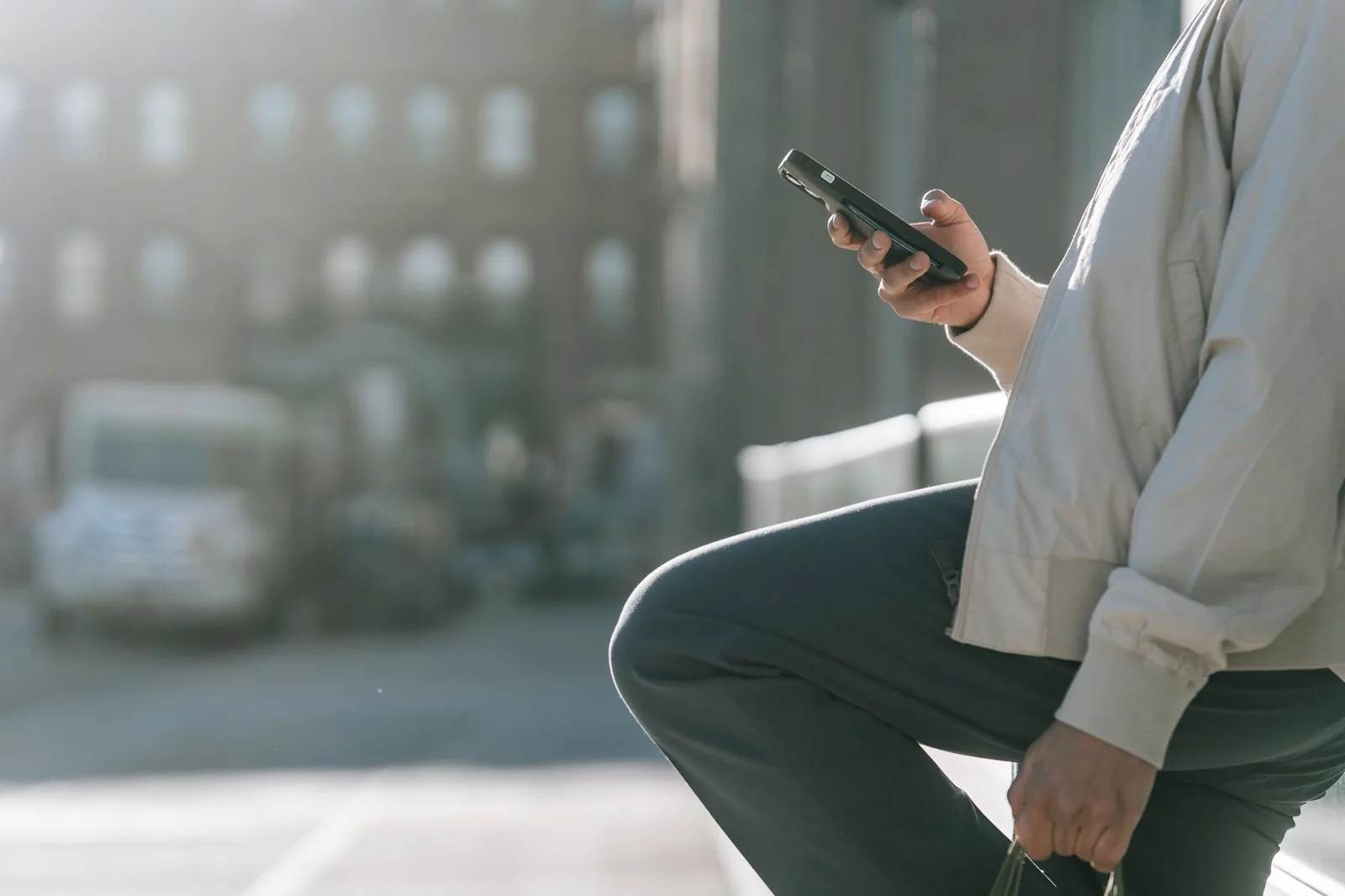 A traveller holding a smartphone on a city street abroad, checking the screen