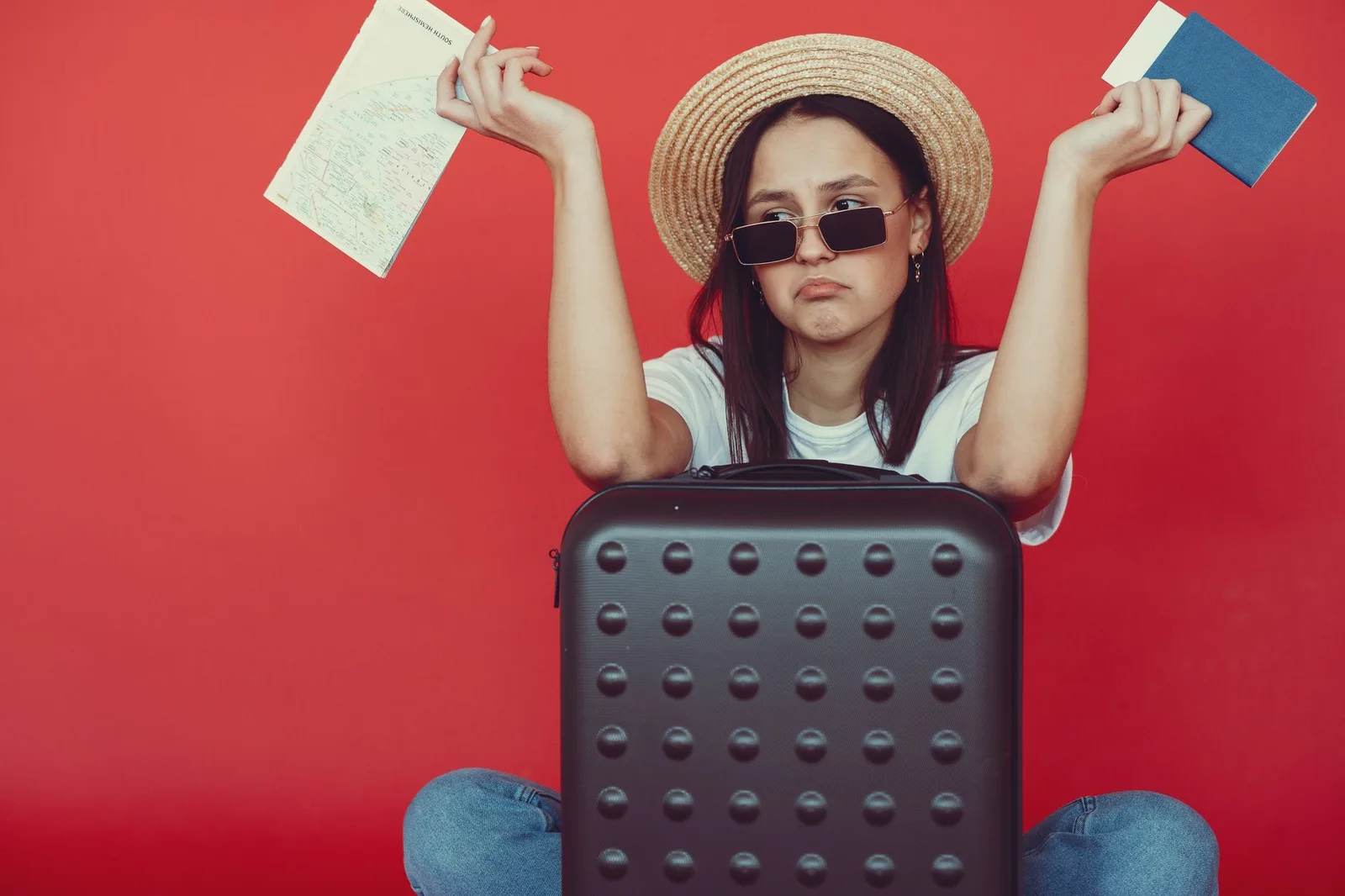 An open suitcase packed for a holiday beside a folded map and a passport — planning a trip