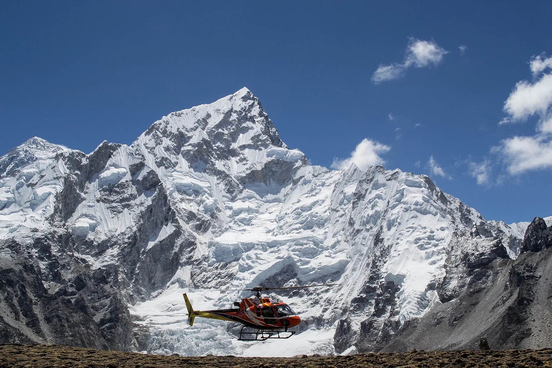 A helicopter departs Everest Base Camp in Nepal's Khumbu region, high beneath the Himalaya — the type of aircraft used for high-altitude long-line rescues.
