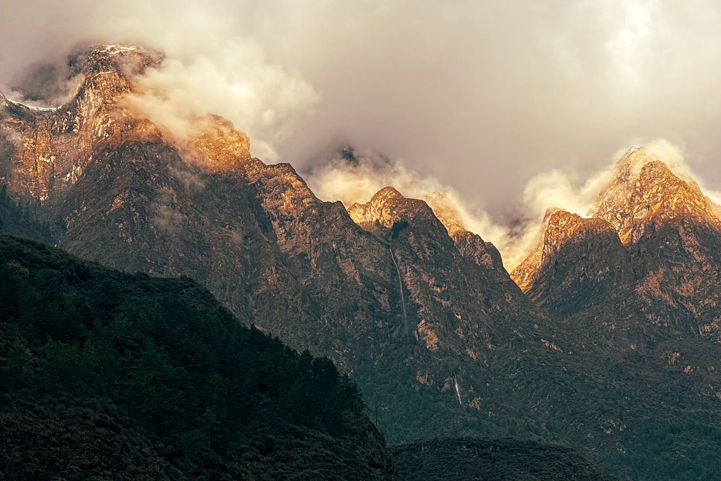 Golden dawn light on a cloud-wrapped Himalayan ridge above the Manaslu trail in Nepal