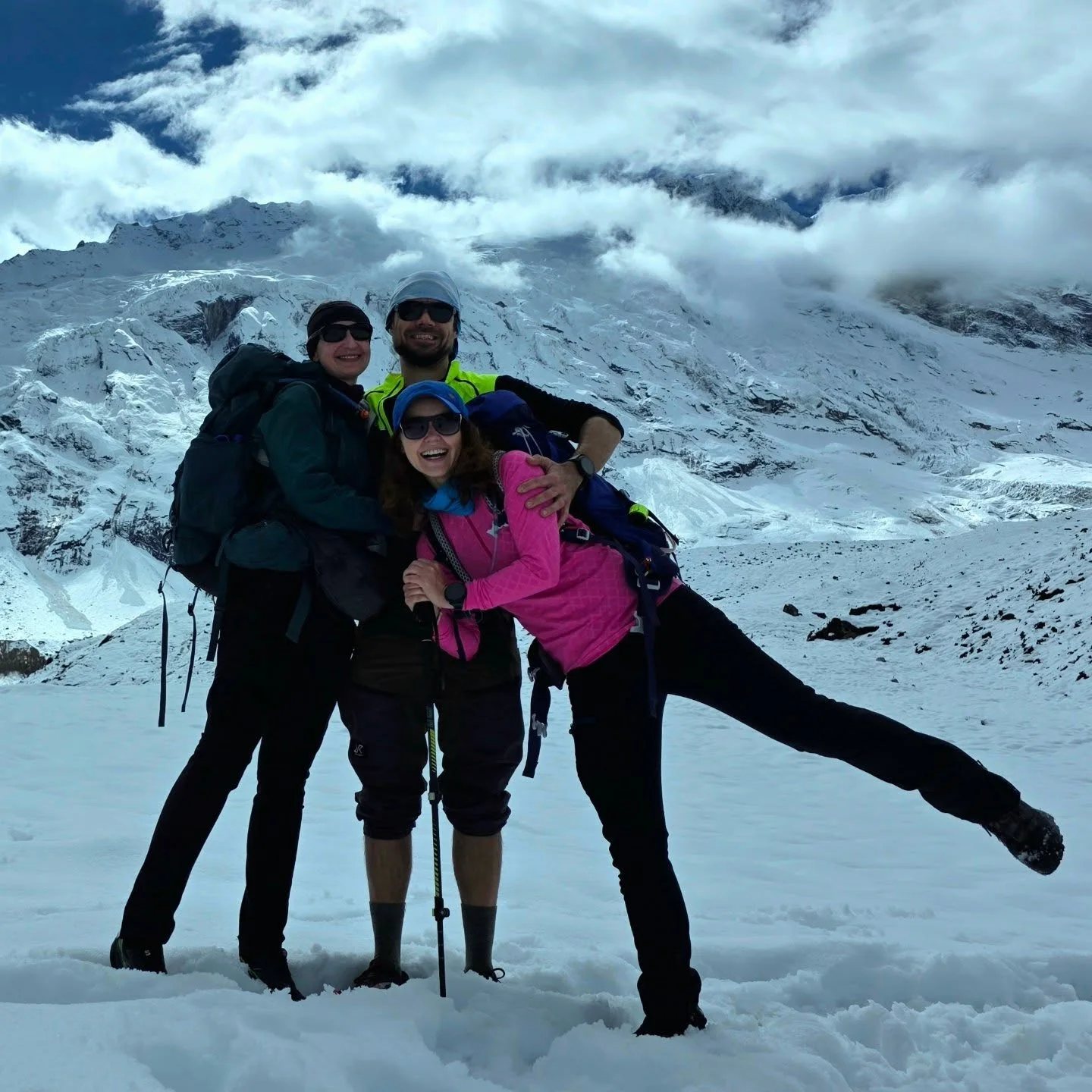 Three trekkers on snow below a high snow face above 4,000m on the Manaslu Circuit in Nepal