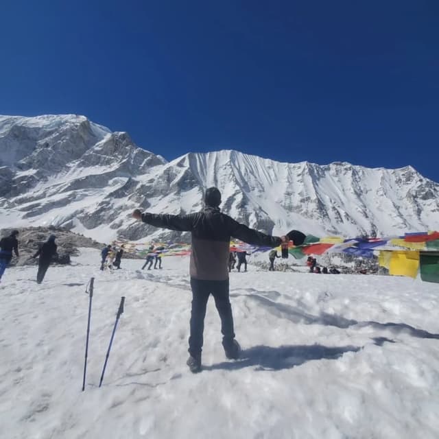 Trekker with arms spread in triumph on the snowy Larkya La pass