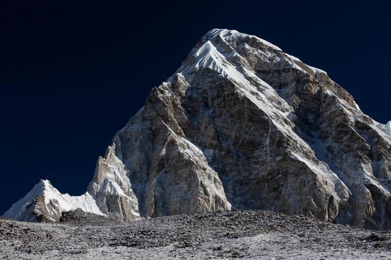Trekker silhouetted on the rocky top of Kala Patthar at dawn